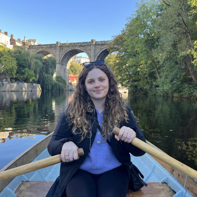 A photograph of Maeve, sitting in a rowing boat and smiling.