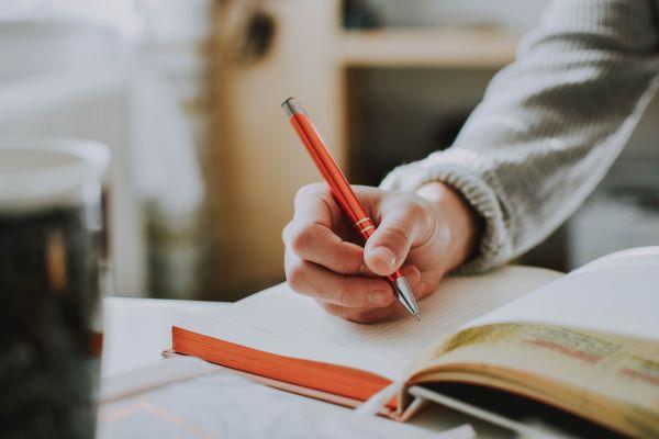 A person writing with a pen