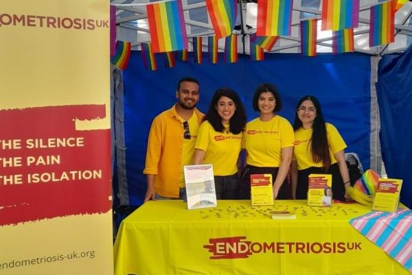 four volunteers at Pride infromation stand. With decorations and leaflets.